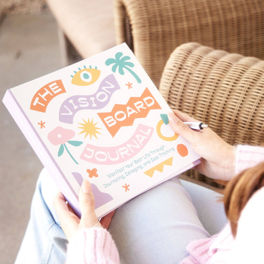 Person holding 'The Vision Board Journal' with colorful design