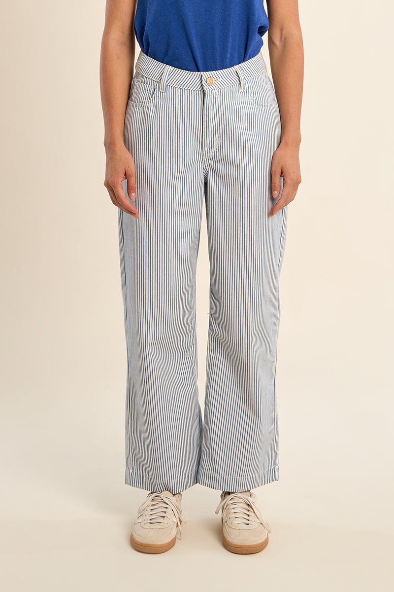 Person wearing blue and white striped pants with a beige background