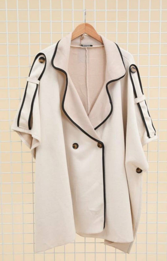 White coat with black trim on a hanger against a tiled wall background