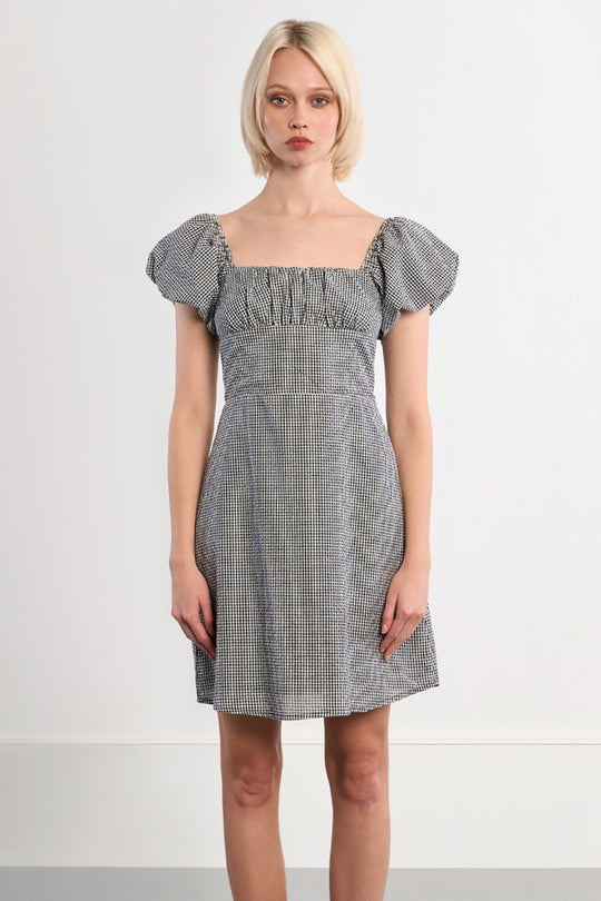 Woman wearing a checkered dress with puff sleeves against a white background