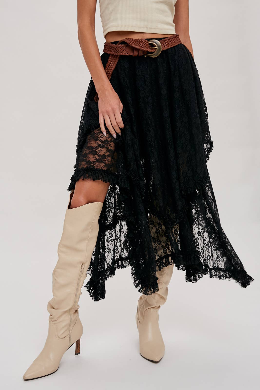 Person wearing a black lace skirt with beige knee-high boots on a white background