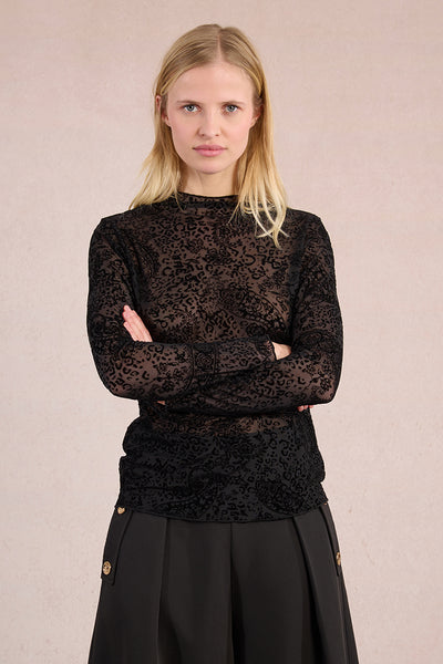 Woman wearing a black lace top with a plain background