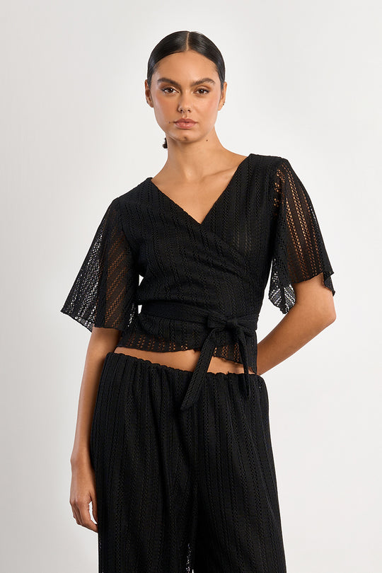 Woman wearing a black outfit with sheer sleeves on a white background