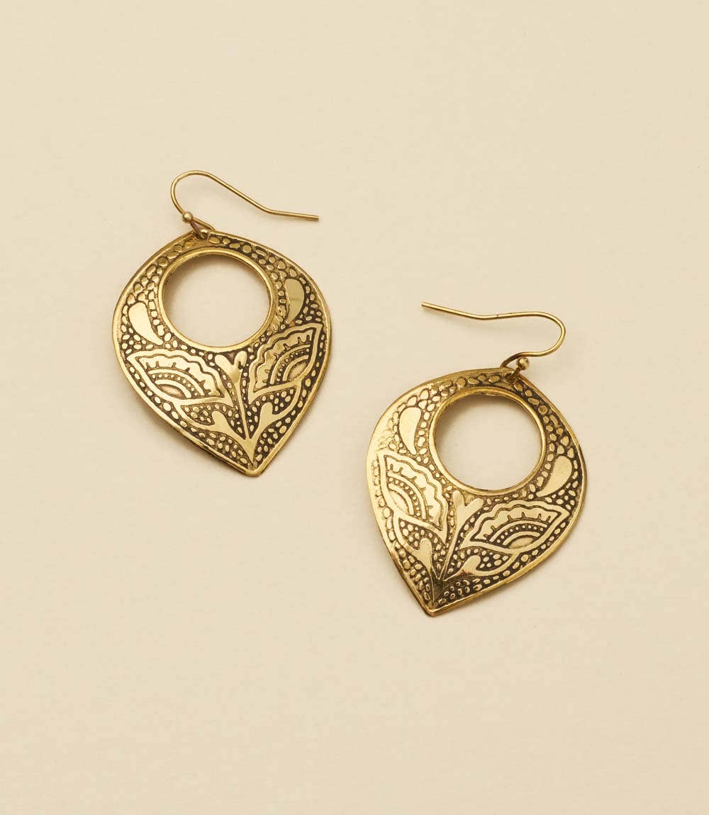 Pair of gold earrings with intricate designs on a beige background