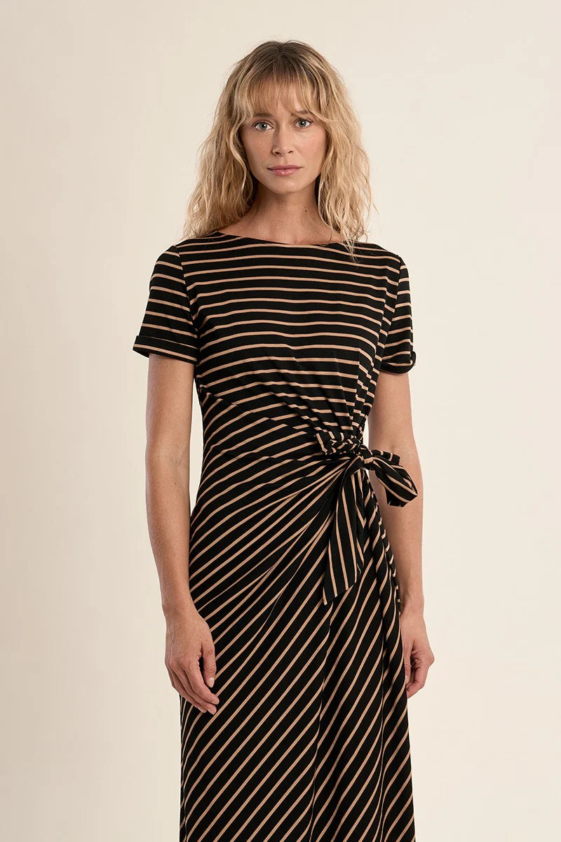 Woman wearing a black and gold striped dress against a beige background