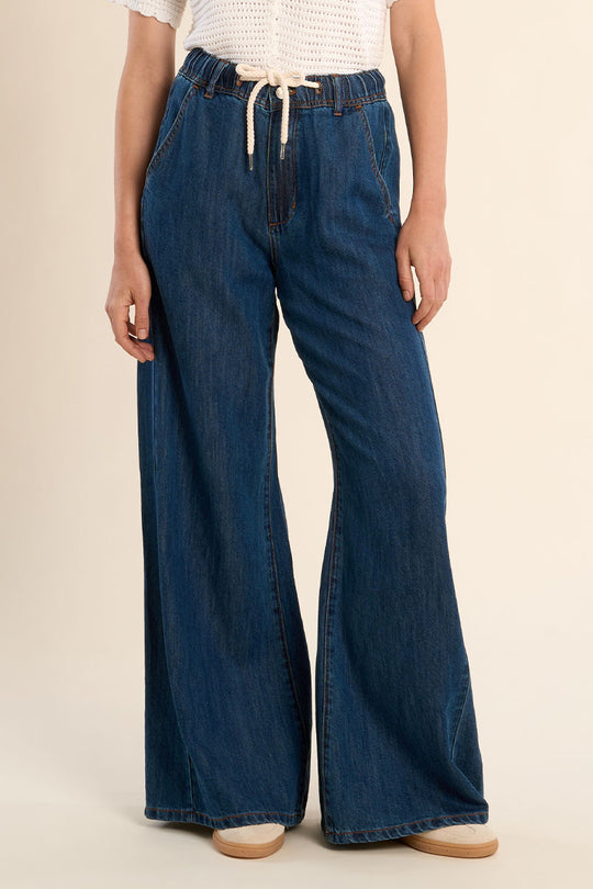Person wearing blue wide-leg jeans on a beige background