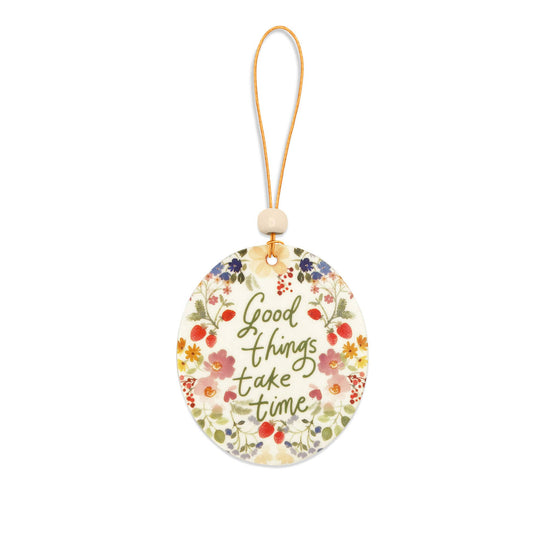 Decorative tag with floral design and 'Good things take time' text on a white background