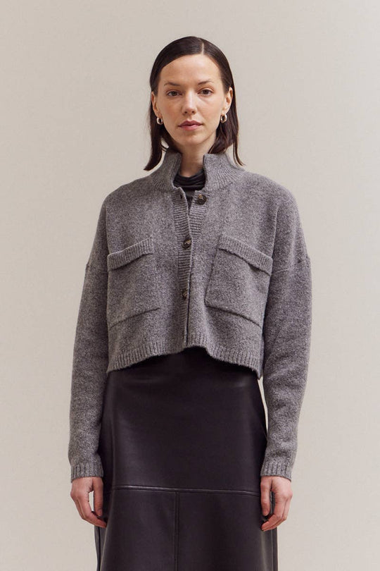 Woman wearing a gray knitted cardigan against a plain background