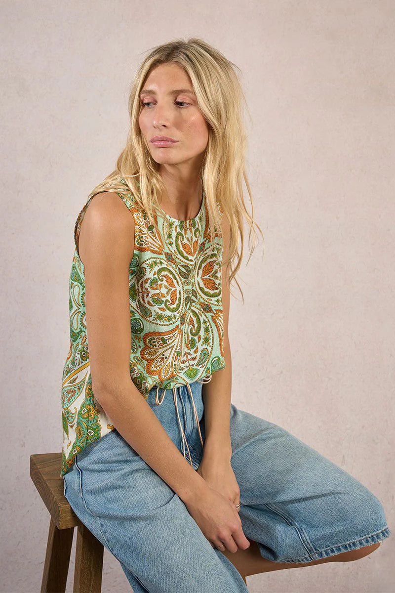 Woman wearing a green and orange blouse paired with denim shorts