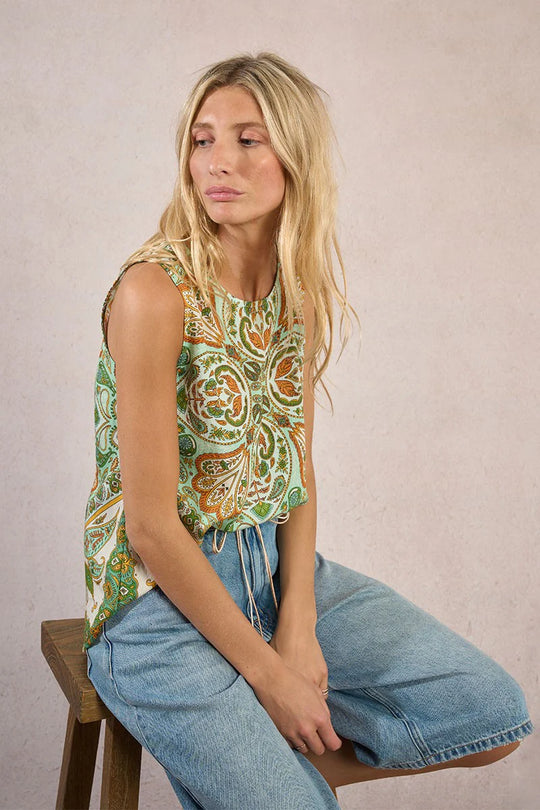 Woman wearing a green and orange blouse paired with denim shorts