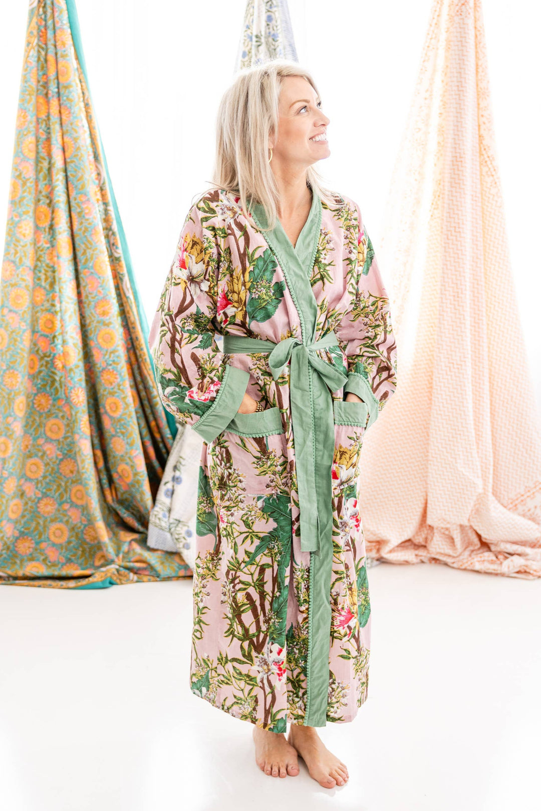 Woman wearing a floral robe with hanging fabric panels in the background