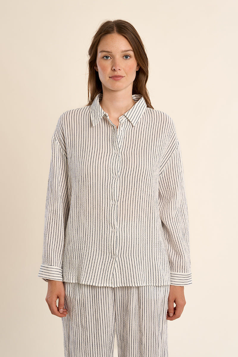 Woman wearing a striped shirt and pants on a beige background