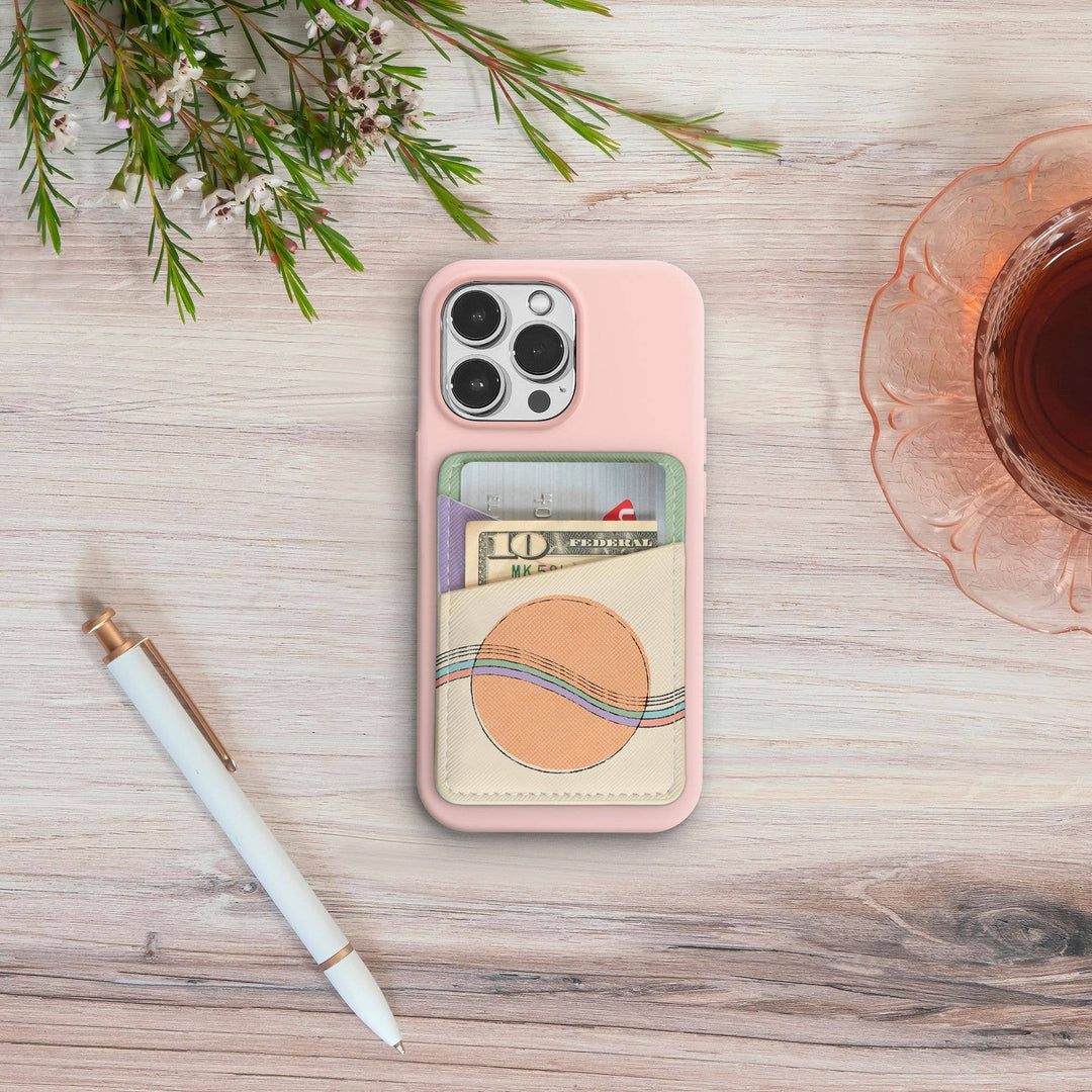 Phone case with card holder on a wooden surface with a pen and flowers