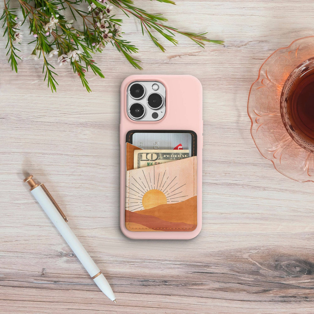 Phone case with card holder on a wooden surface with a pen and tea.