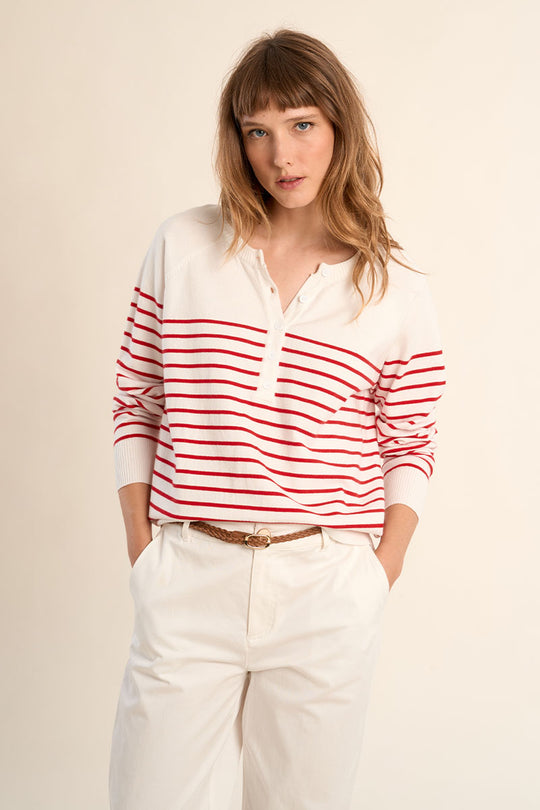 Woman wearing a red and white striped shirt with white pants on a beige background