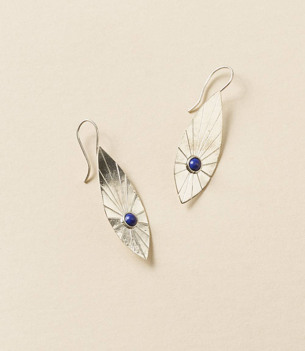 Pair of silver earrings with blue gemstones on a beige background