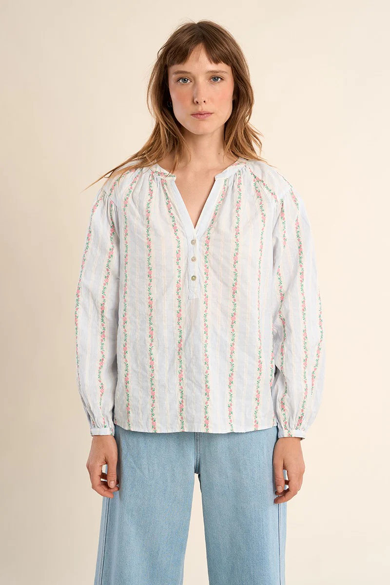 Woman wearing a white blouse with colorful patterns on a beige background