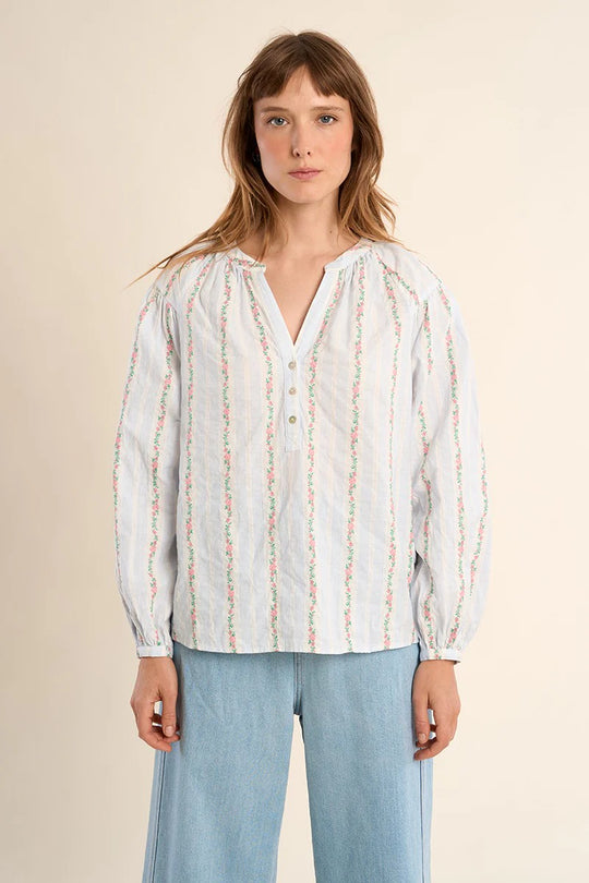 Woman wearing a white blouse with colorful patterns on a beige background
