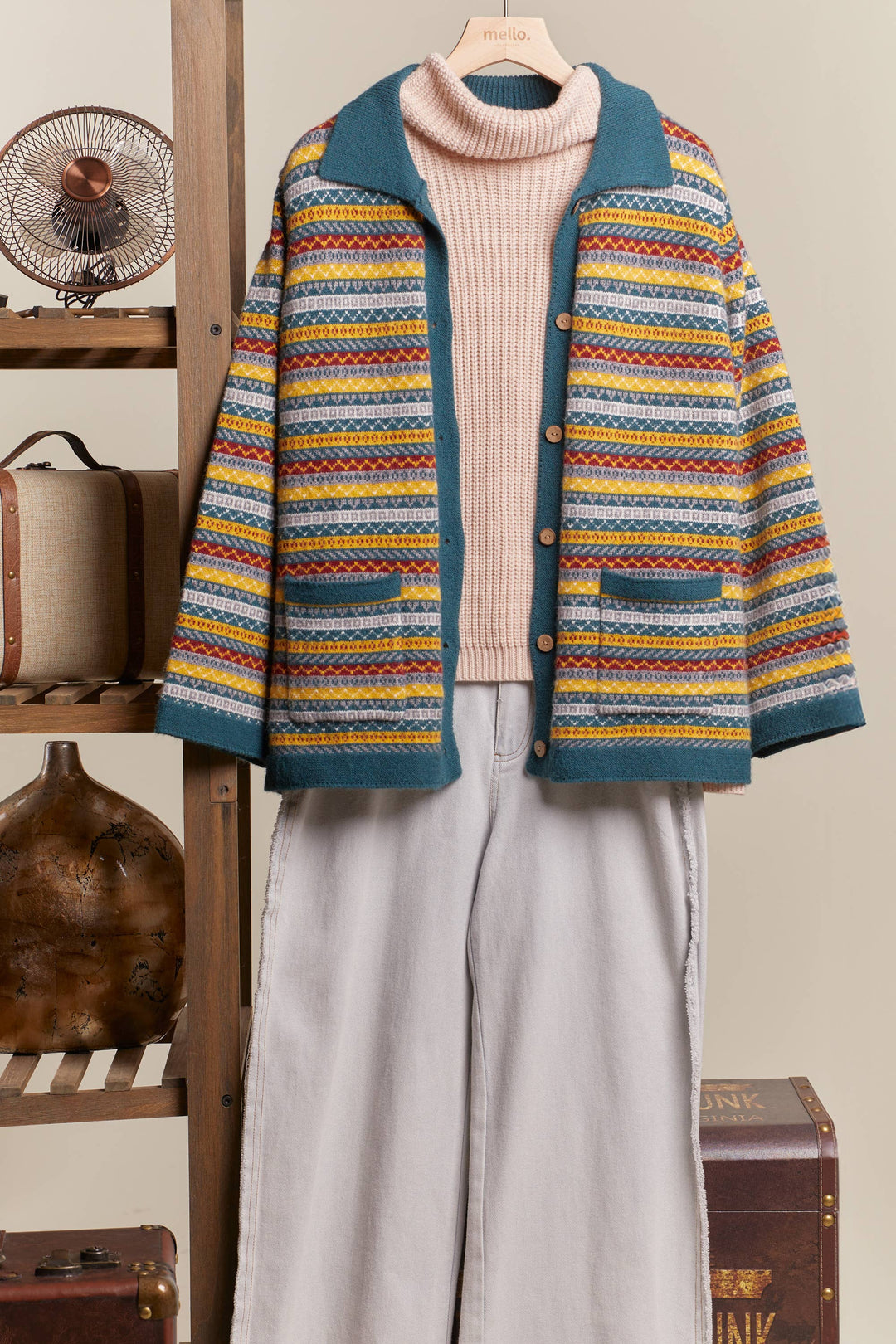 Colorful striped cardigan over a pink turtleneck sweater with light pants, on a neutral background.