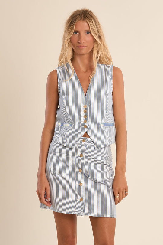 Woman wearing a light blue striped dress with buttons on a beige background