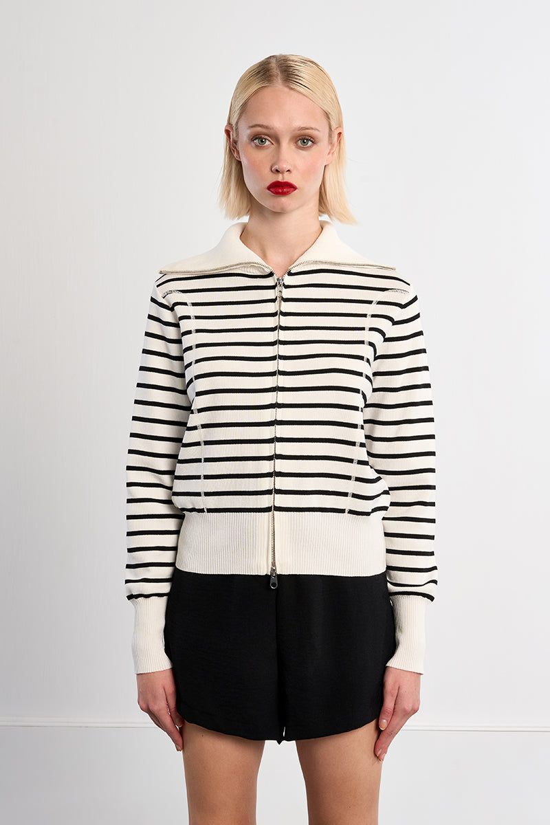 Woman wearing a black and white striped jacket on a plain background