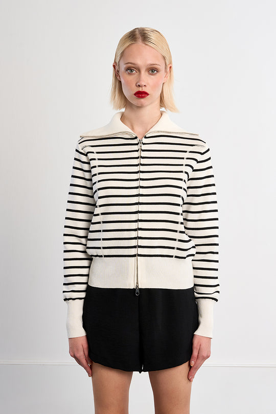 Woman wearing a black and white striped jacket on a plain background