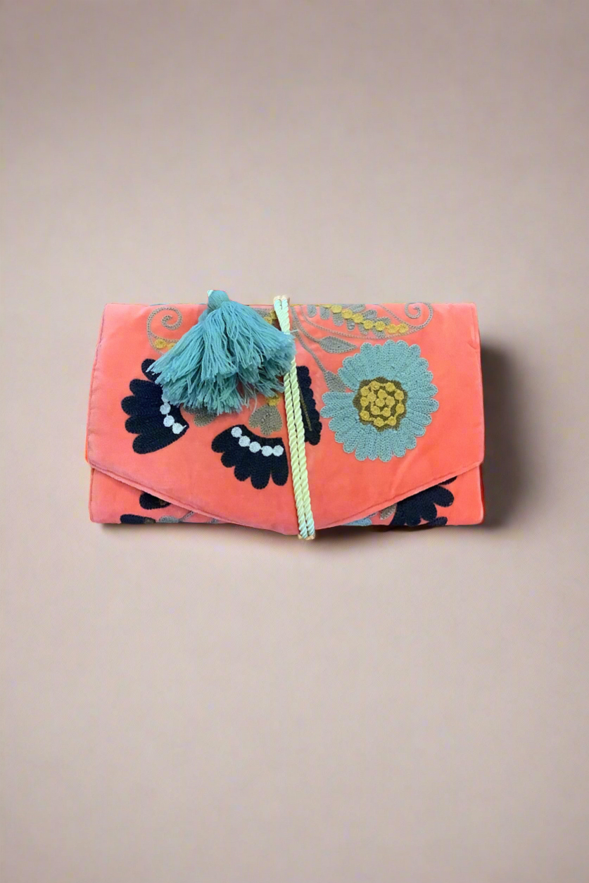 Floral patterned clutch bag with tassel on a beige background