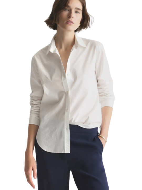 Woman wearing a white button-up shirt and navy pants on a white background