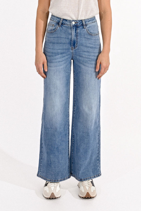 Person wearing blue wide-leg jeans on a white background